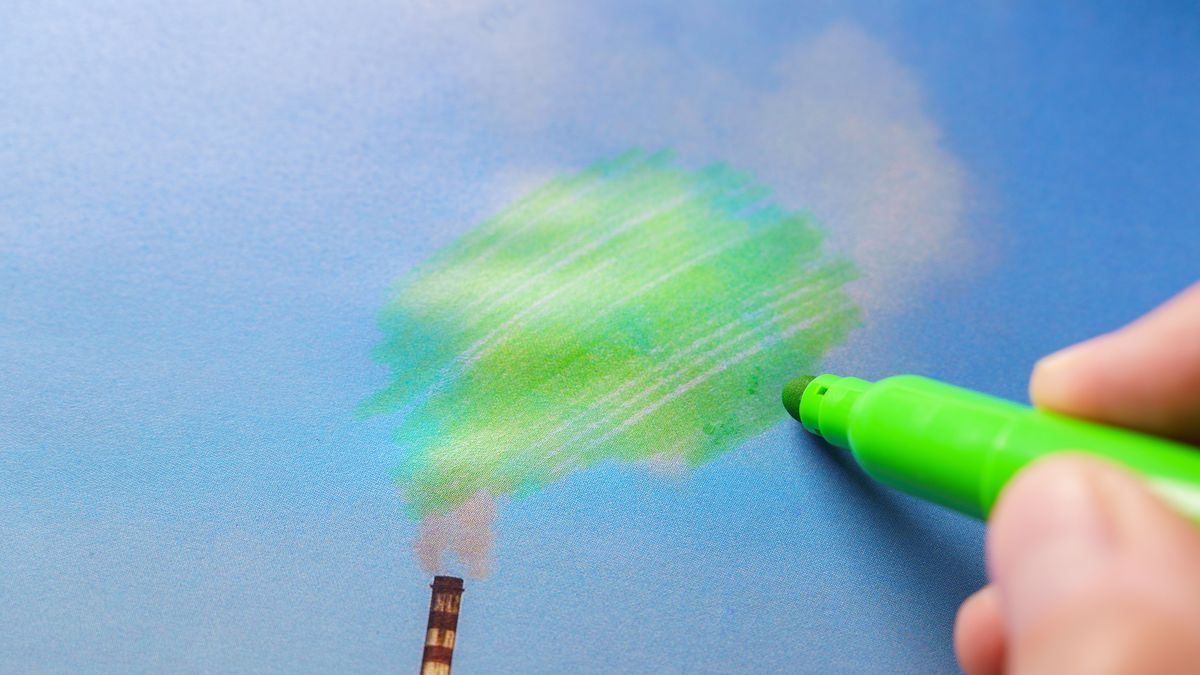 A hand with a green pen drawing over the smoke from a smokestack, to represent greenwashing.